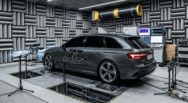 Car on a dynamometer inside an acoustic test chamber with microphones and sensors for performance analysis
